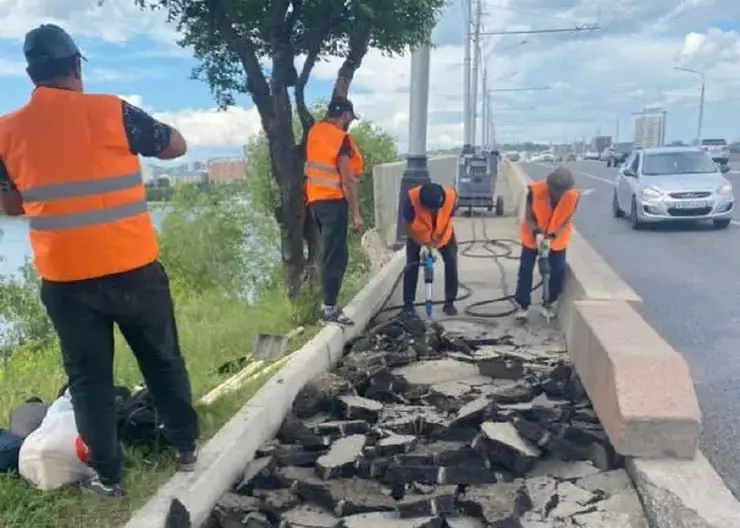 В Красноярске рабочие убирают старый асфальт с тротуара на Коммунальном мосту