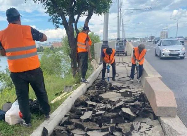 В Красноярске рабочие убирают старый асфальт с тротуара на Коммунальном мосту